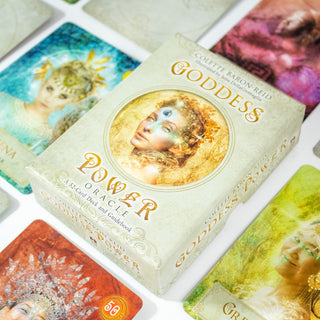 Box of the Goddess Power Oracle Deck by Colette Baron Reid. Box is tan with a woman shown surrounded by gold and stars in the center. Other cards from the deck surround it.
