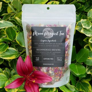 Moon Magick organic herbal loose leaf tea in package with black label and a full moon. Against foliage and flower background