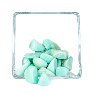 Fifteen tumbled aqua colored Amazonite tumbled pocket stones in a glass bowl with white background. 