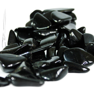 Several black tourmaline tumbled pocket stones for energetic protection, in natural variation of sizes and shapes.