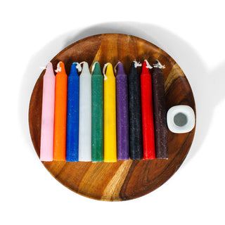 Set of 10 rainbow colored chime candles lined up on a circular wooden plate with a white ceramic chime holder, against a white background.