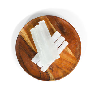 Several white raw selenite sticks on wooden plate. 