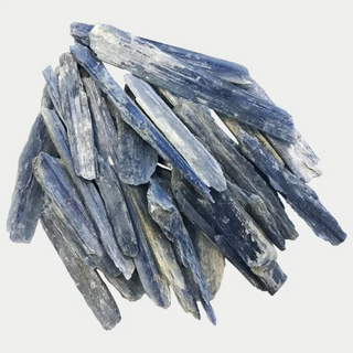 Several dozen pieces of raw blue kyanite. Each piece is rectangular shaped and irregular. Shades of light blue.