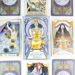 The Dreamscape Oracle deck box is in the center. It shows a Black woman in a thrne, wearing a golden dress and holding the scales of justice. She wears a flower crone. Other cards from the deck are around it