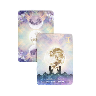 The Full Moon in Gemini card shows the mirror image of a woman with her hands in prayer with a large full moon behind her. A second card in the background shows the back of the cards with three full moons and crystals at each corner.