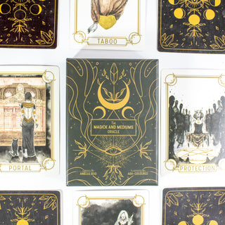 The Magick and Mediums Oracle Deck box is black with golden drawings of crescent moons, crystals and eyes. Other cards from the deck surround it.