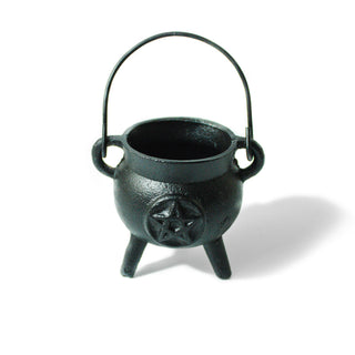 Black cast iron cauldron with a handle on three legs. A pentagram is engraved on the front.  
