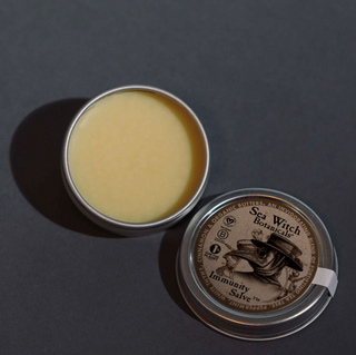 Open tin of immunity salve showing the buttery contents and lid with label