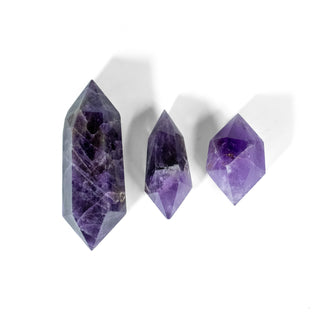 Three double terminated amethysts with points at each end. Each is a different color of purple and of varying sizes showing the natural variations of the crystal.