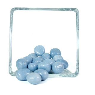 A handful of light sky blue Angelite tumbled pocket stones in a glass bowl on white background.