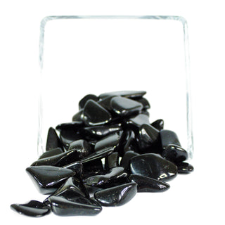 Several black tourmaline tumbled pocket stones for energetic protection, in natural variation of sizes and shapes.