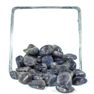Deep blue tumbled iolite pocket stones with natural variation in color in a glass bowl.