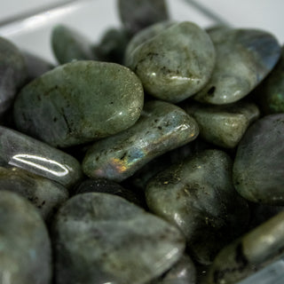 Close up of labradorite tumbled pocket stones showing the rainbow flash of orange and pink. 