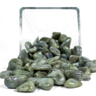 Several labradorite tumbled pocket stones in hues of green and blue in a glass bowl.