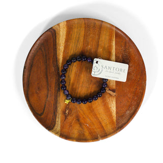 Deep purple beaded crystal mala bracelet with brass charm and tag.