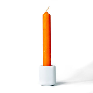 Orange chime candle for spellwork and intention setting, set in a white ceramic candle holder with white background.