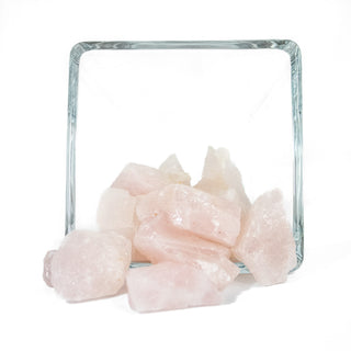 Several pieces of raw rose quartz in varying sizes and natural shapes. Natural stone is light pink.