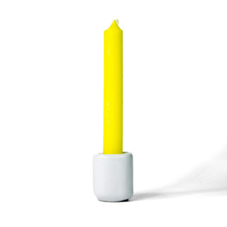 Yellow chime candle for spellwork and intention setting, set in a white ceramic candle holder with white background.