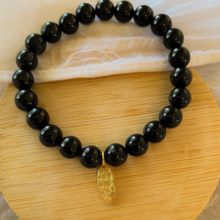 Beaded black tourmaline gemstone bracelet for energetic protection. Beads are glossy black with brass charm. 