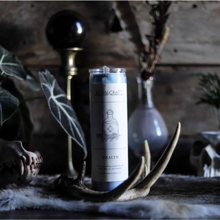Health 7 day ritual candle in a dark witchy setting with antlers and plants,