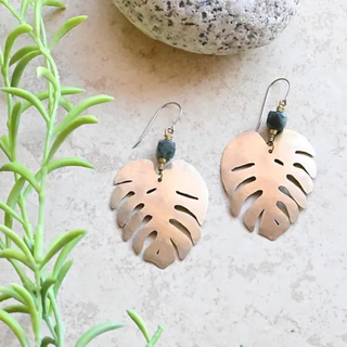 Pair of brass earrings in the shape of monstera leaves. A Green Labradorite bead is at the top of each leaf. 