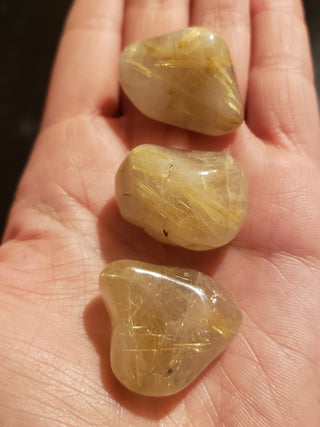 Several rutilated quartz tumbled pocket stones showing natural variations of light yellow and gold.