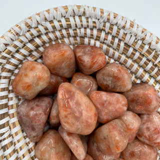 Several tumbled sunstone pocket stones showing natural variations of color of orange, reds and yellows