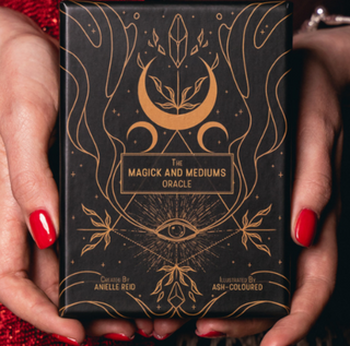 Two hands holding the box of the Magick and Mediums Oracle deck