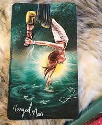 The hanged Man card from the light seer's tarot shows a woman hanging over water with a bright light behind her head
