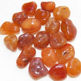 Close up of a dozen tumbled carnelian pocket stones in shades of red and orange.
